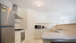 A modern kitchen with a stainless steel refrigerator, stove, oven, microwave, and a sink.