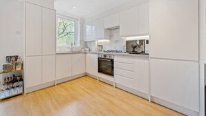 Een moderne keuken met witte kasten, een ingebouwde oven en een houten vloer.
