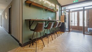 A modern interior with a bar area, wooden flooring, and a green accent wall with a neon sign.