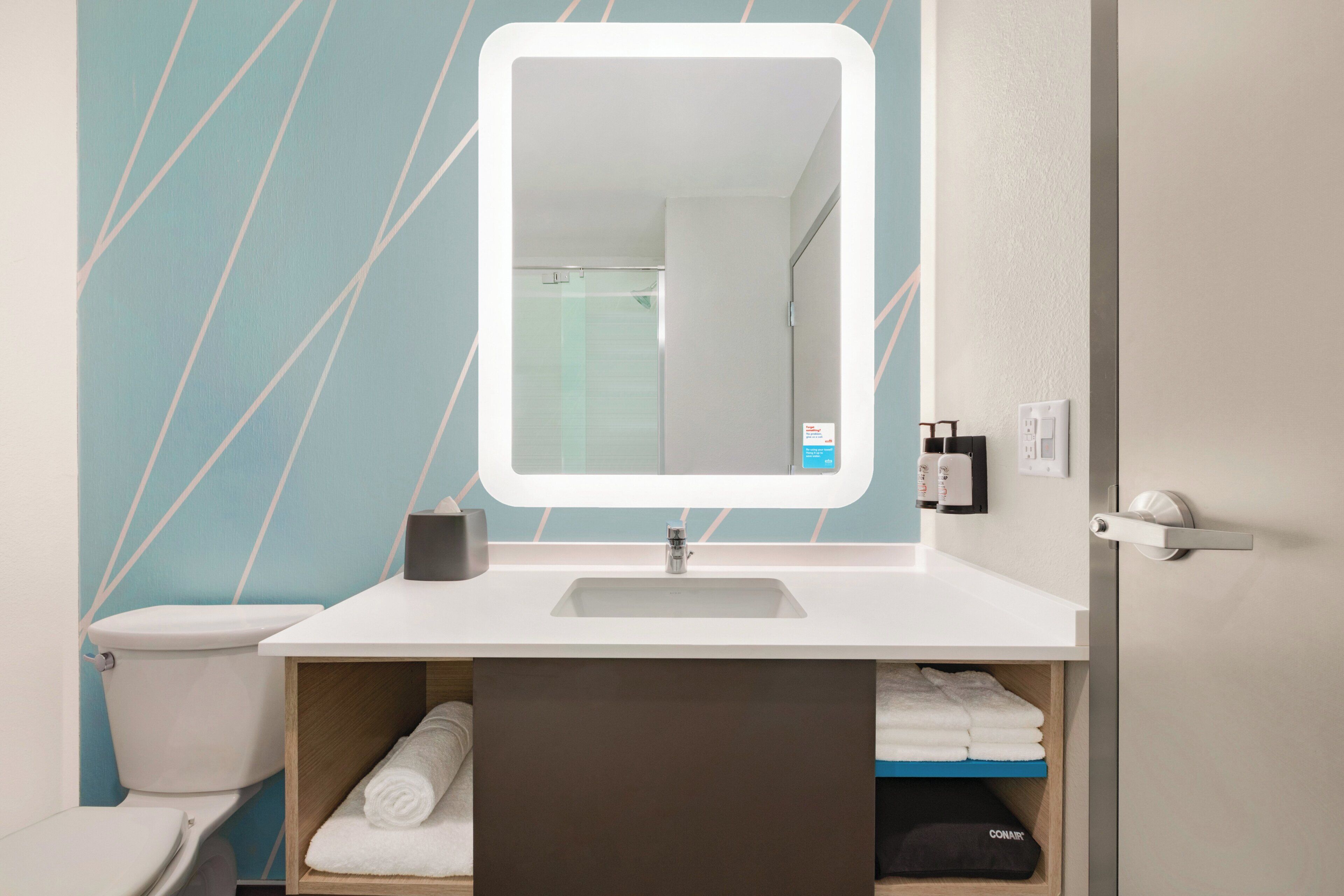 A bathroom with a white sink, a mirror, and a towel rack.