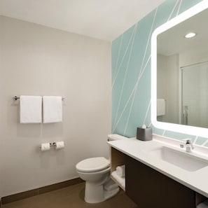 A modern bathroom with a toilet, sink, and mirror. There are two towels on the wall and a tissue box on the counter. - avid hotel CHATTANOOGA SOUTH - RINGGOLD by IHG (Ringgold)