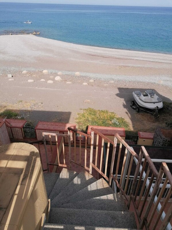 A staircase leading to a beach with a boat on the sand.