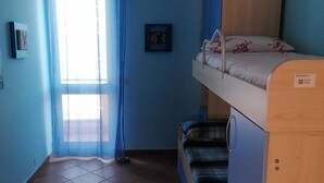 A room with a bunk bed, a window with blue curtains, and a tiled floor.
