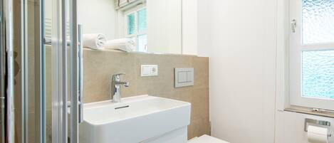 Un baño moderno con un lavamanos blanco, un inodoro y una ventana con vistas.