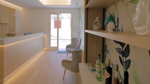 Un'area di accoglienza con una scrivania in legno, una sedia e una parete con mensole che espongono oggetti decorativi.