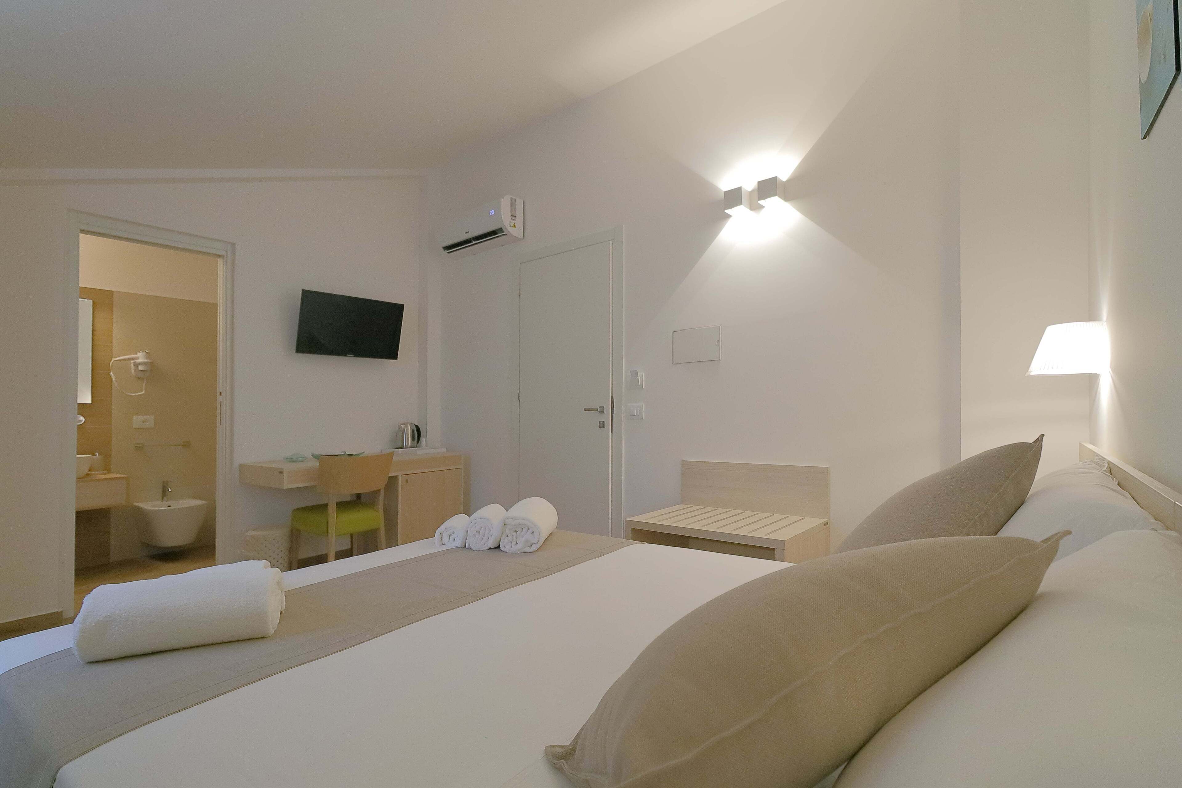 Ein Hotelzimmer mit Bett, Fernseher, Badezimmer und Schreibtisch.