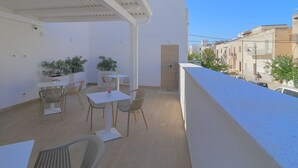 Un balcone con sedute all'aperto, piante in vaso e vista sulla città.