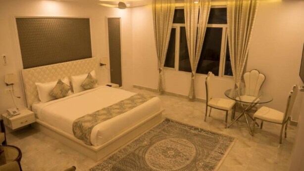 A modern hotel room with a large bed, a glass table, and a chair. - Hotel Blue Waves (Port Blair)