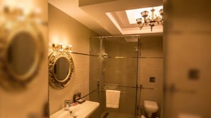A modern bathroom with a glass-enclosed shower, a vanity with a mirror, and a chandelier. - Hotel Blue Waves (Port Blair)