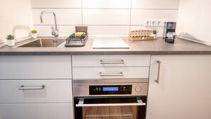 A modern kitchen with a stainless steel sink, a built-in oven, and a digital clock displaying 21:13. - Premium Studio | 1 Min to HBF (Mannheim)
