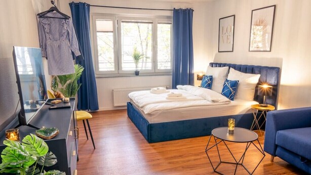 A modern bedroom with a bed, a sofa, a desk, and a mirror. - Premium Studio | 1 Min to HBF (Mannheim)