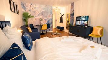 A hotel room with a large bed, a desk, a TV, and a seating area with chairs.