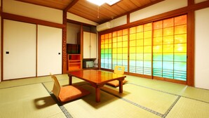 Una habitación japonesa tradicional con suelo de tatami, una mesa de madera baja y puertas correderas.