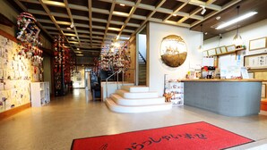 Vestíbulo de hotel con alfombra roja, una escalera y un mostrador de recepción.