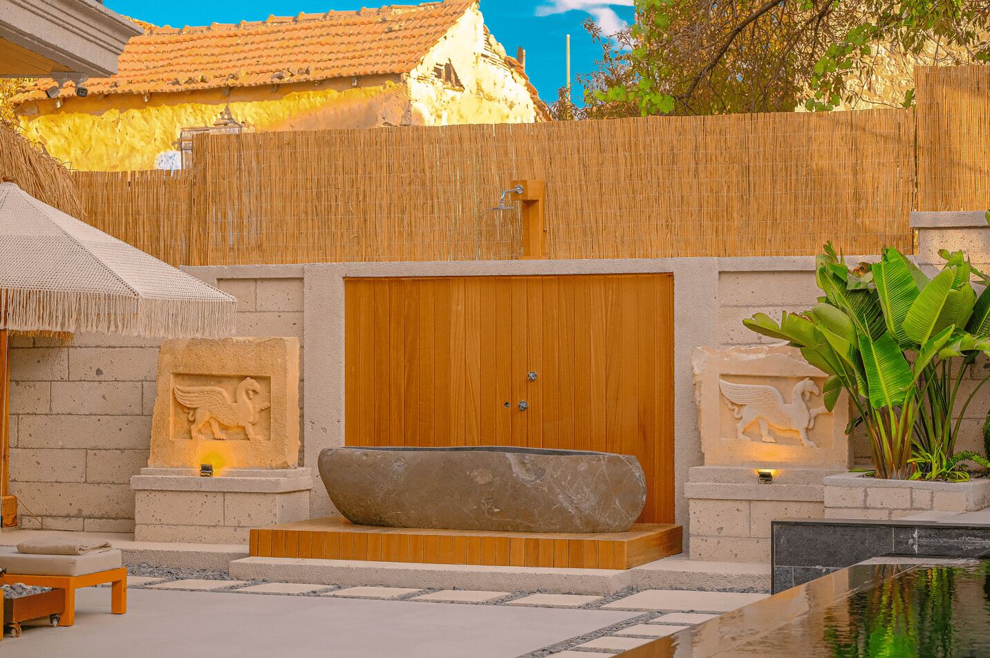 Un área de spa con una puerta de madera, una pila de piedra y una pequeña piscina.