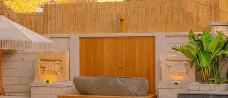 Un área de spa con una puerta de madera, una pila de piedra y una pequeña piscina.