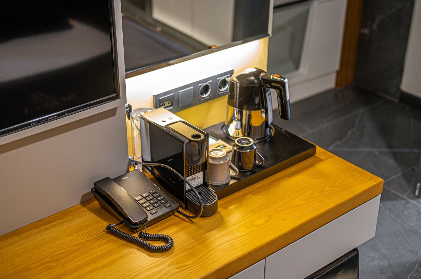 Una encimera de cocina con una cafetera, una jarra de café, un molinillo de café y un teléfono.