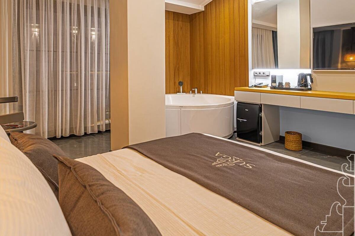 Habitación de hotel con cama, baño con bañera, lavamanos y espejo.