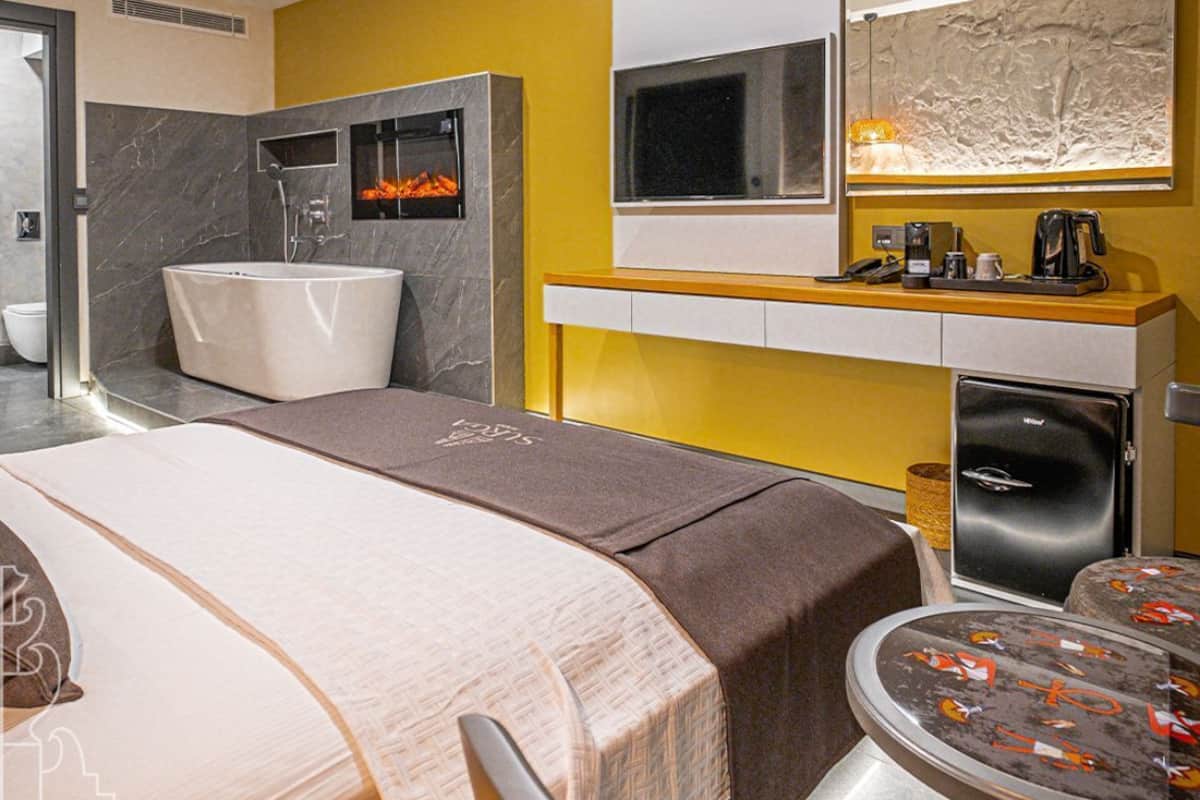 Una habitación de hotel moderna con una cama grande, una bañera integrada, microondas y refrigerador.