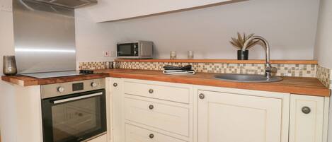 A compact kitchen with a microwave, oven, and stainless steel range hood.