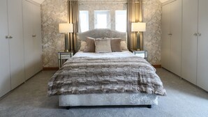 A bedroom with a large bed, two bedside tables with lamps, a wardrobe, and a window with curtains. - Old Print House (Ilkeston)