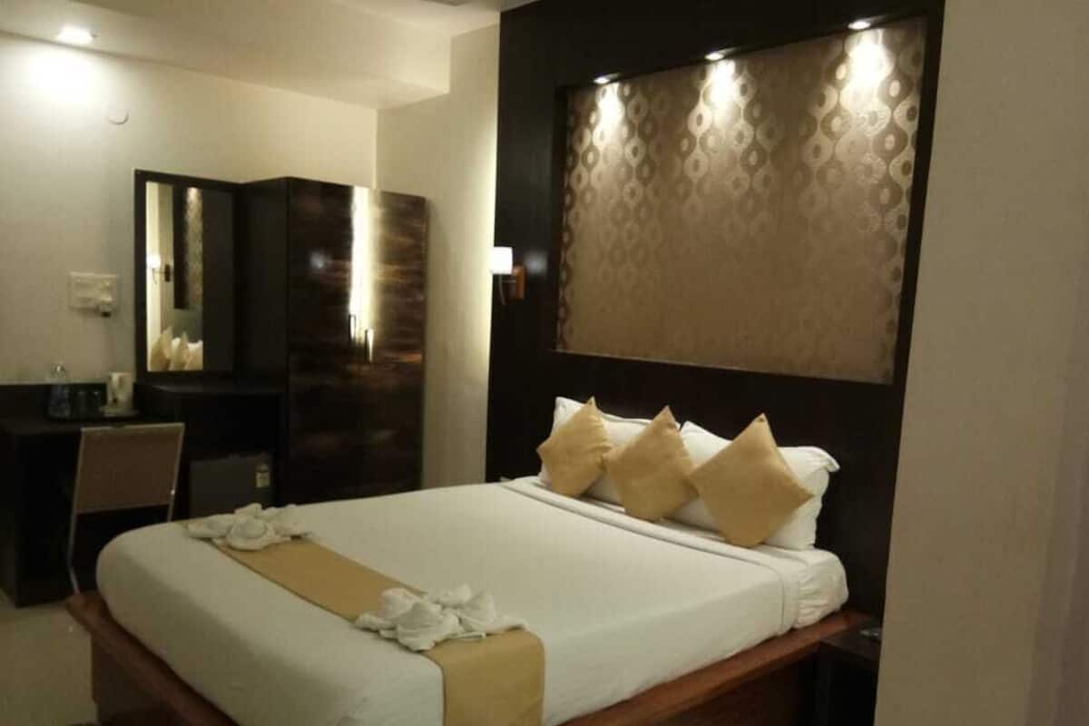 A hotel room with a large bed, a desk, and a mirror.