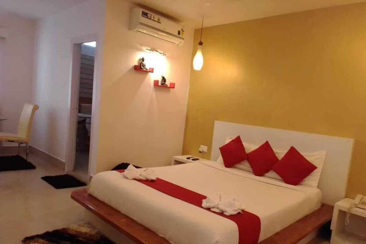 A hotel room with a bed, bedside table, and a small desk with a chair.