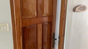 A wooden door with a handle and a small plaque on the wall. - Airport Hotel (Port Blair)