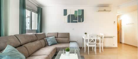 Een moderne woonkamer met een bank, salontafel en een eethoek.