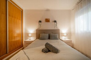 A bedroom with a large bed, two bedside tables, and a wooden wardrobe.