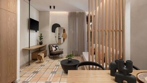 Un salon moderne avec un plancher en bois, une table basse ronde, un canapé et un téléviseur fixé au mur.