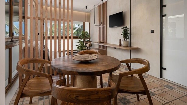 A modern dining area with a round wooden table, four wooden chairs, and a decorative bowl.
