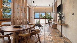 A modern dining area with wooden furniture, large windows, and potted plants.