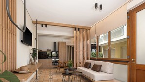 A modern kitchen with a built-in stove, a dining area with a wooden table and chairs, and a seating area with a sofa and cushions.
