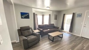 A spacious living room with a brown leather sofa, a brown leather armchair, and a wooden coffee table.