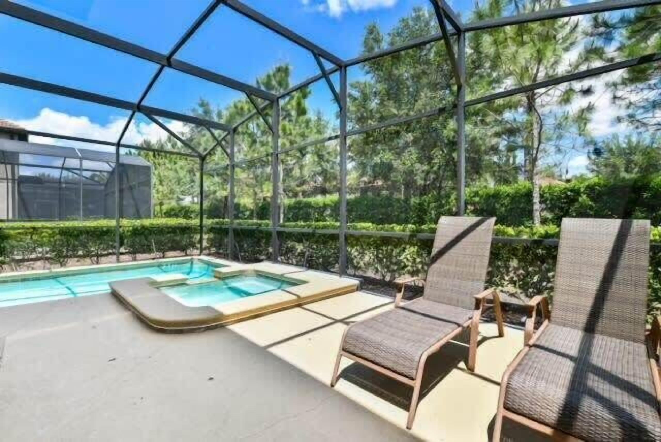 Un área de piscina al aire libre con paredes de vidrio, sillones de descanso y un jacuzzi.