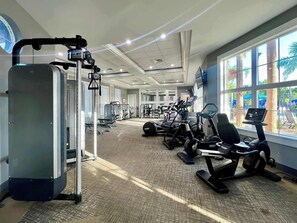 A gym with cardio machines, weight machines, and a large exercise ball.