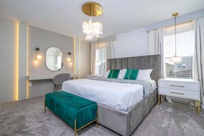 Un dormitorio moderno con una cama grande, mesitas de noche, un tocador y un espejo.