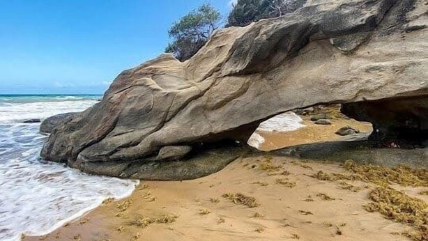 A rocky beach with a lighthouse on top of a large rock formation. - Faro Penthouse | Beachfront with Stunning Views (Maunabo)