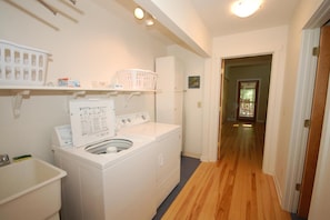 A laundry room with a washer and dryer, a white sink, and shelves with laundry supplies. - Dune Path - with Waterfront! (Empire)