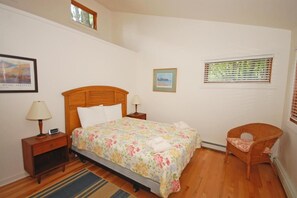 Un dormitorio con una cama de madera, una mesita de noche con lámpara, una silla y una ventana con persianas.