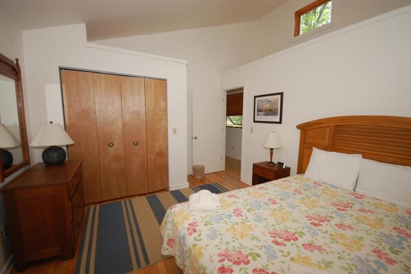 A bedroom with a bed, a wooden wardrobe, a nightstand, a lamp, and a framed picture on the wall. - Dune Path - with Waterfront! (Empire)