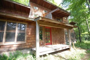 A rustic wooden cabin with a red door, large windows, and a porch. - Dune Path - with Waterfront! (Empire)