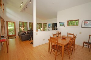 A spacious living area with a dining table and chairs, a sofa, and a kitchen counter.