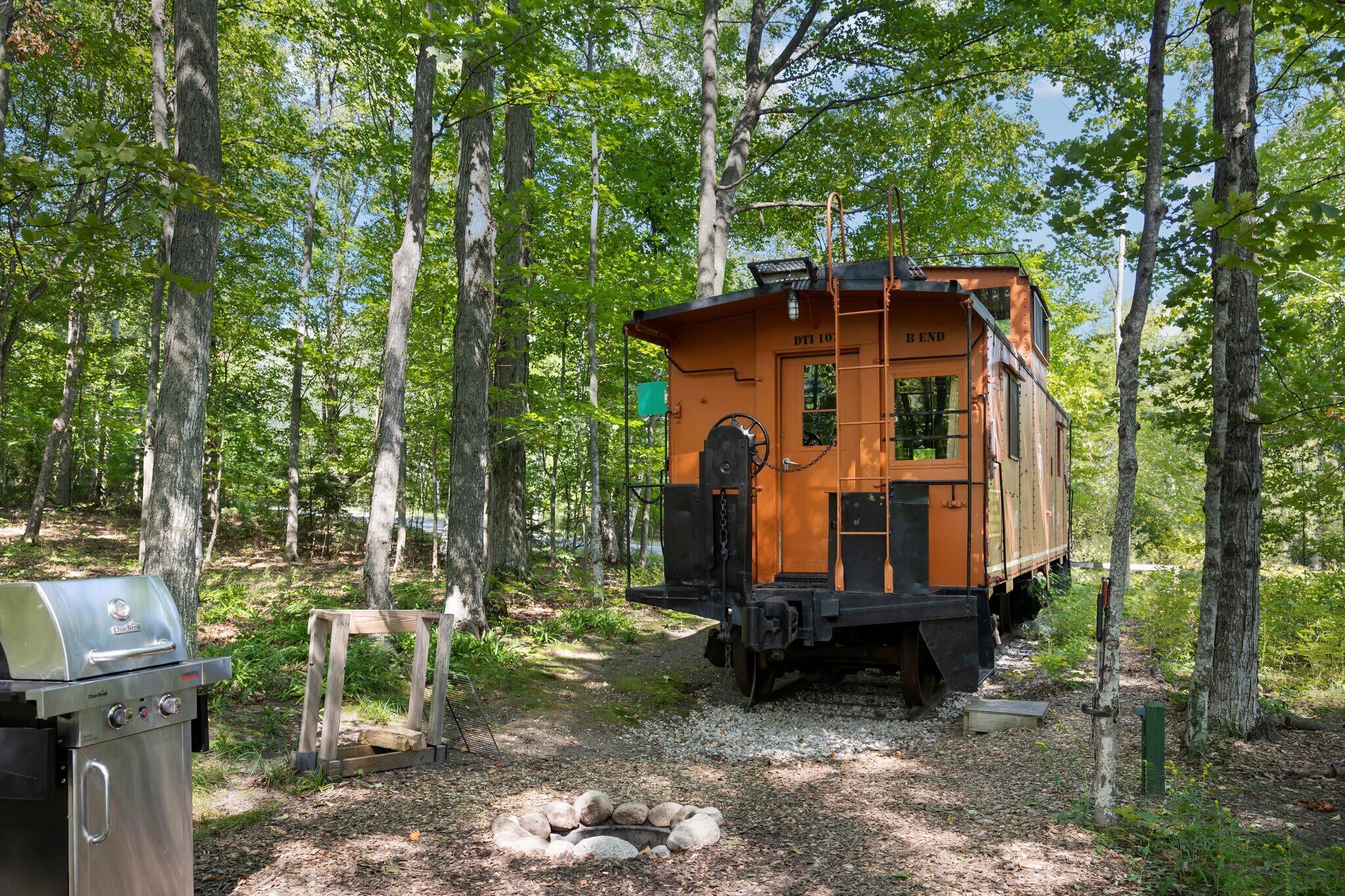 A vintage train car converted into a cabin with a grill and a small table.