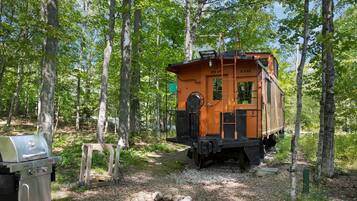 A vintage train car converted into a cabin with a grill and a small table.