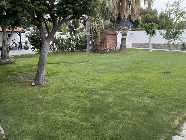 A well-maintained grassy area with trees and a small wooden structure.