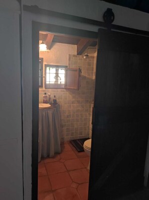 A bathroom with a tiled floor, a sink, a toilet, and a window.
