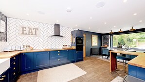 Une cuisine moderne avec des armoires bleues, un dosseret orné d’un motif en chevrons et une grande fenêtre offrant une vue sur l’extérieur.