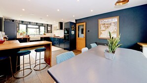 Une cuisine moderne avec un coin bar, une table à manger et des chaises bleues.
